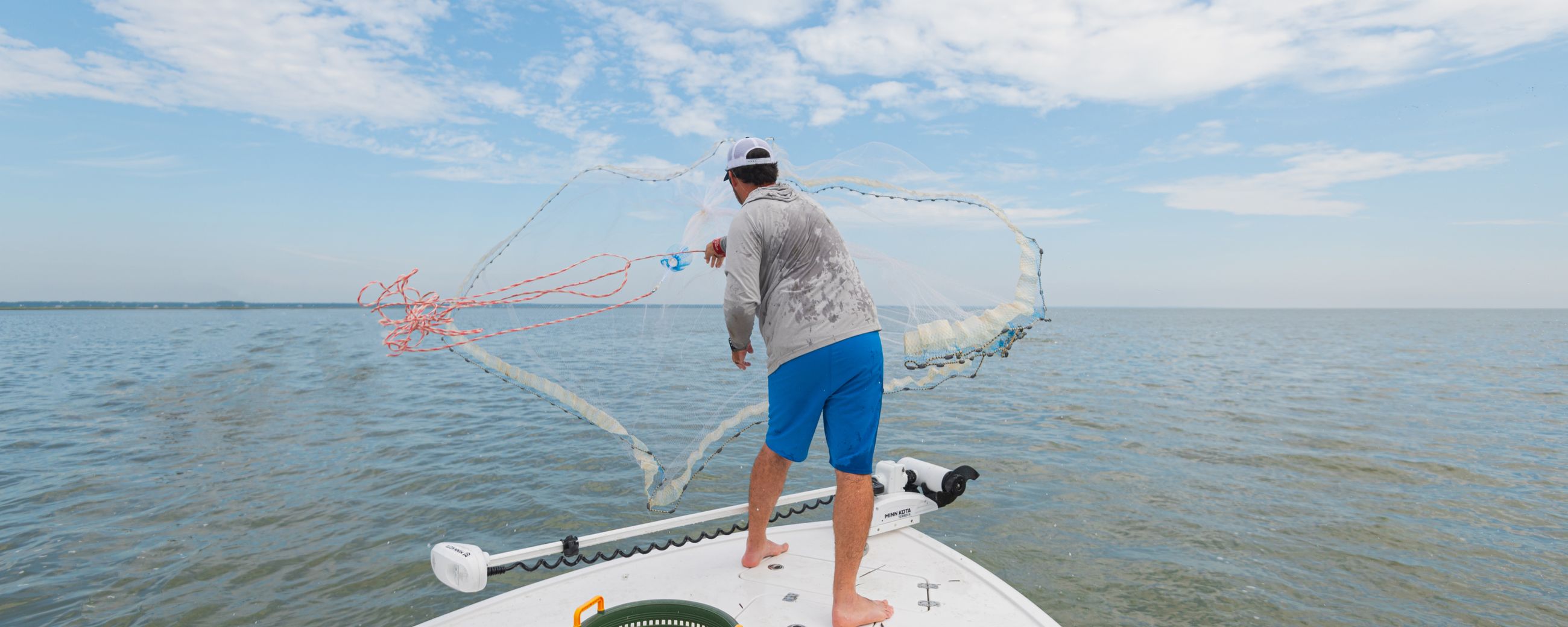 Young boy reeling in a fish offshore wearing a blue jacket