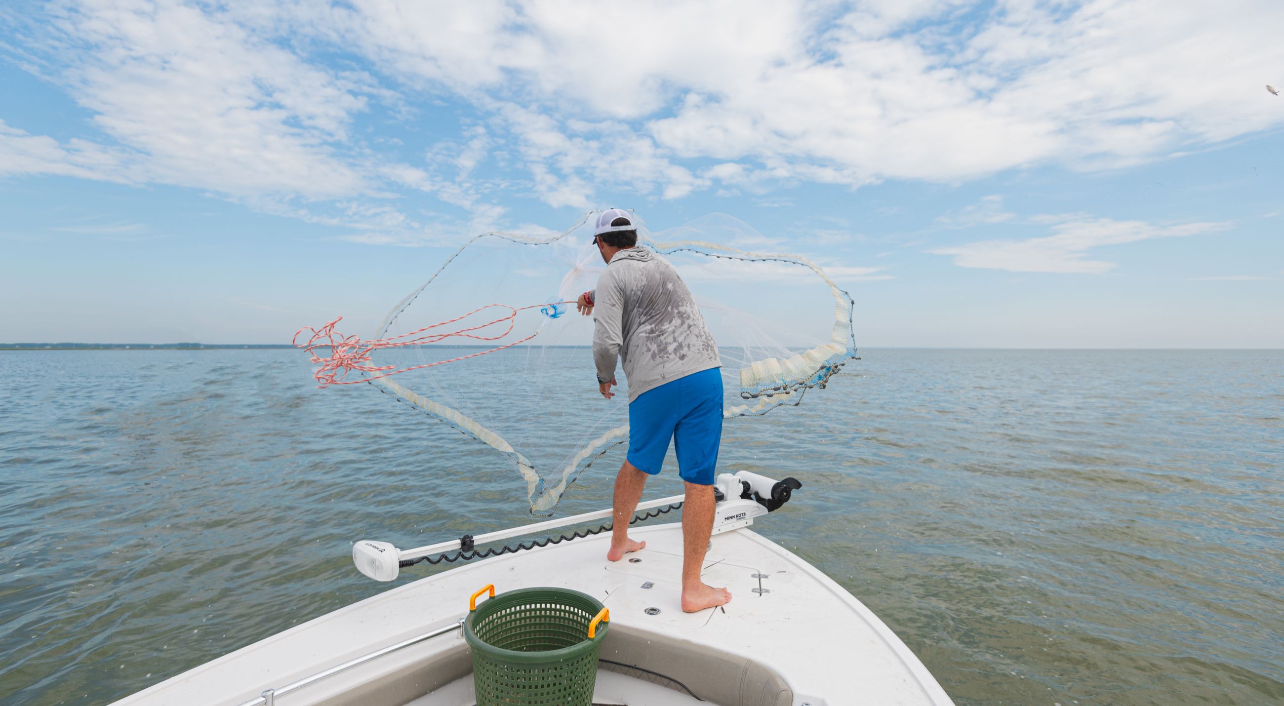 Young boy reeling in a fish offshore wearing a blue jacket